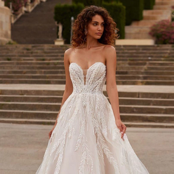 Model walking outside in a lace and bead a-line wedding dress.