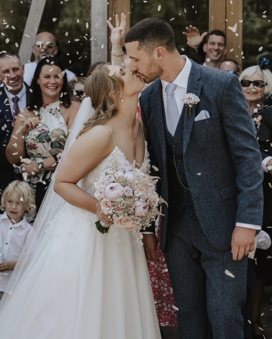 Bride and groom kissing with confetti falling around them